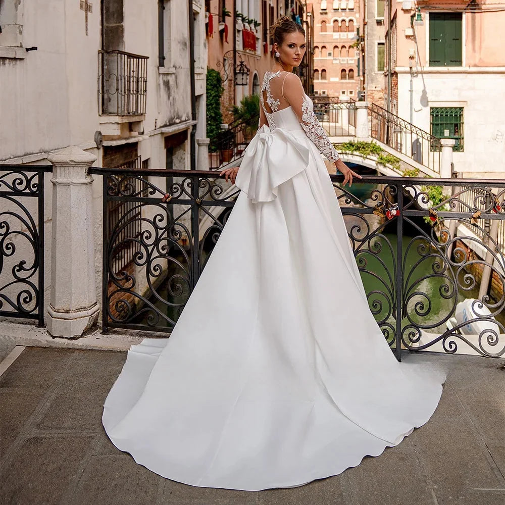 Elegantes Satin -Hochzeitskleid für Braut lange Ärmeln runde Nackenapplikationen Rücken Big Bow Korsett Brautkleid Ein Liniendesign